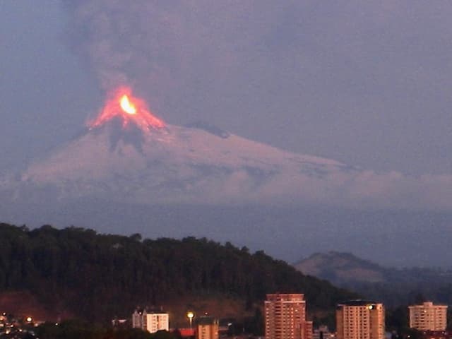 Volcanic eruption in mountains behind a residential building